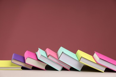 Photo of Many colorful books on beige table against pink background, space for text