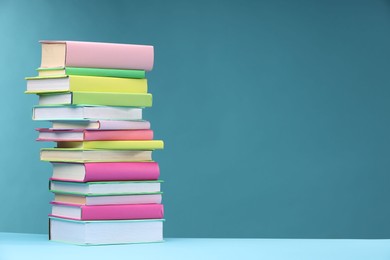 Stack of colorful books on light blue background, space for text