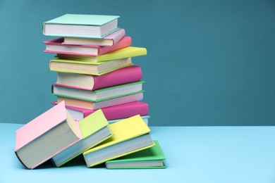 Photo of Stack of colorful books on light blue background, space for text