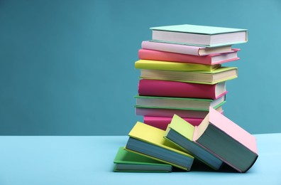 Photo of Stack of colorful books on light blue background, space for text