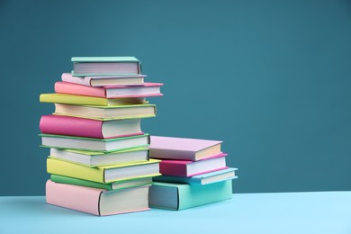 Photo of Stacks of colorful books on light blue background, space for text