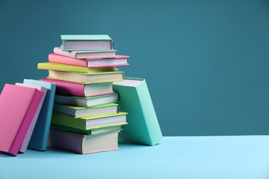 Photo of Stack of colorful books on light blue background, space for text