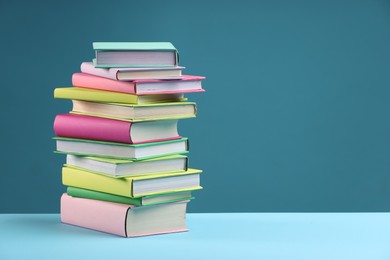 Stack of colorful books on light blue background, space for text