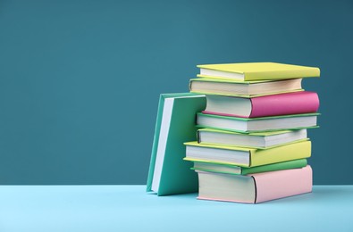 Stack of colorful books on light blue background, space for text