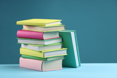 Stack of colorful books on light blue background, space for text