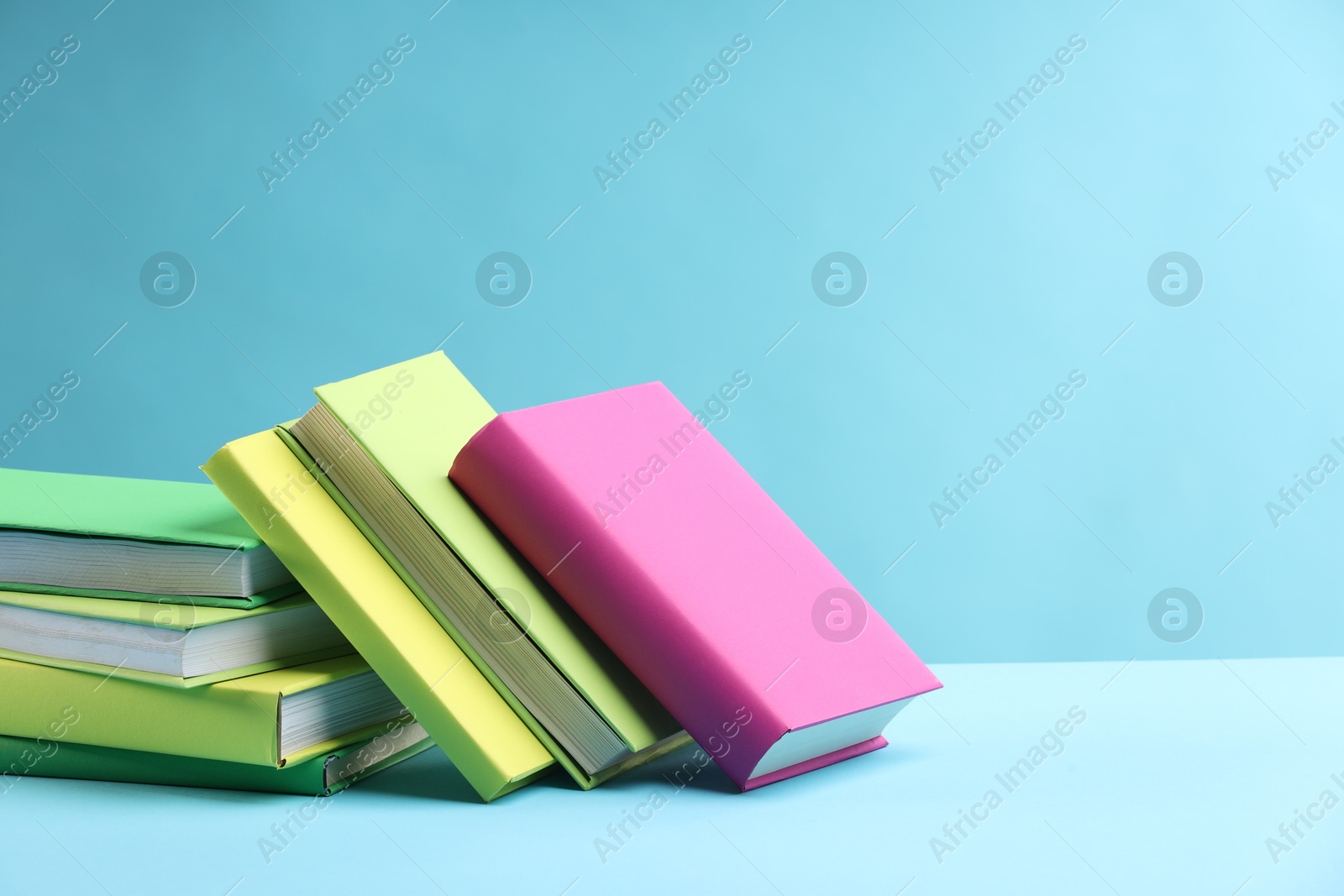 Photo of Many colorful books on light blue background, space for text