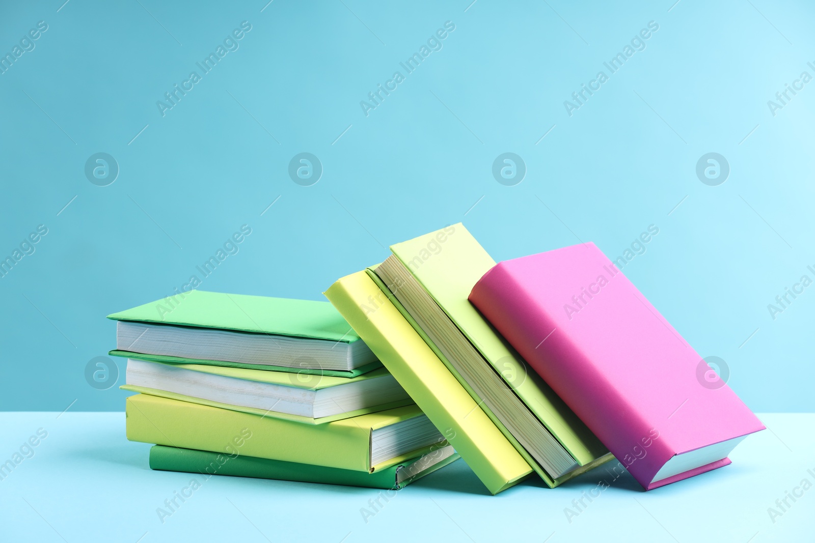 Photo of Many colorful books on light blue background, space for text