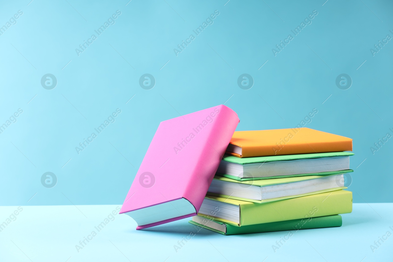 Photo of Many colorful books on light blue background, space for text