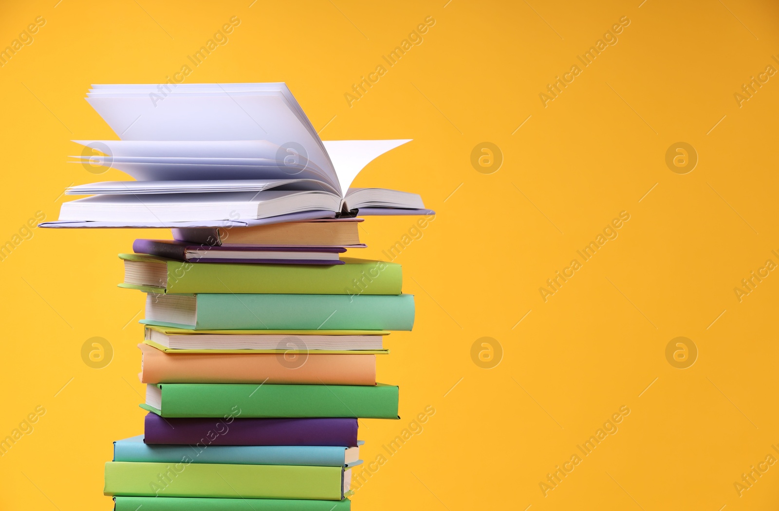 Photo of Stack of colorful books on orange background, space for text