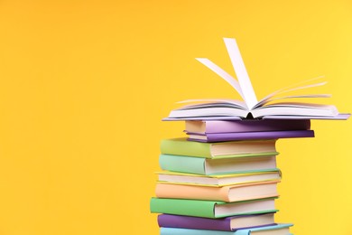 Photo of Stack of colorful books on yellow background, space for text