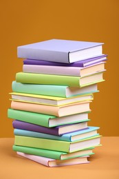 Photo of Stack of colorful books on orange background