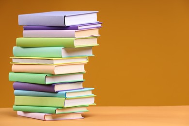 Photo of Stack of colorful books on orange background, space for text