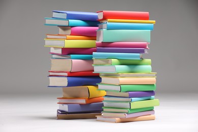 Photo of Stacks of colorful books on light grey background