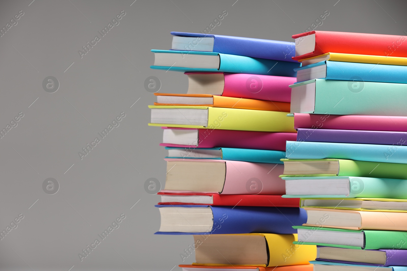 Photo of Stacks of colorful books on light grey background, space for text