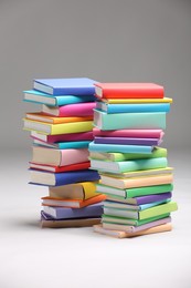 Photo of Stacks of colorful books on light grey background