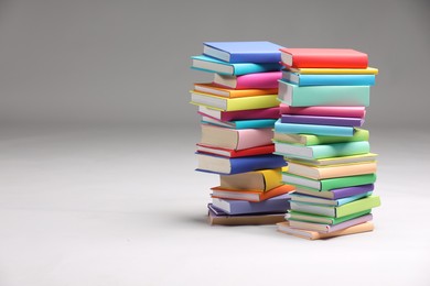 Photo of Stacks of colorful books on light grey background, space for text