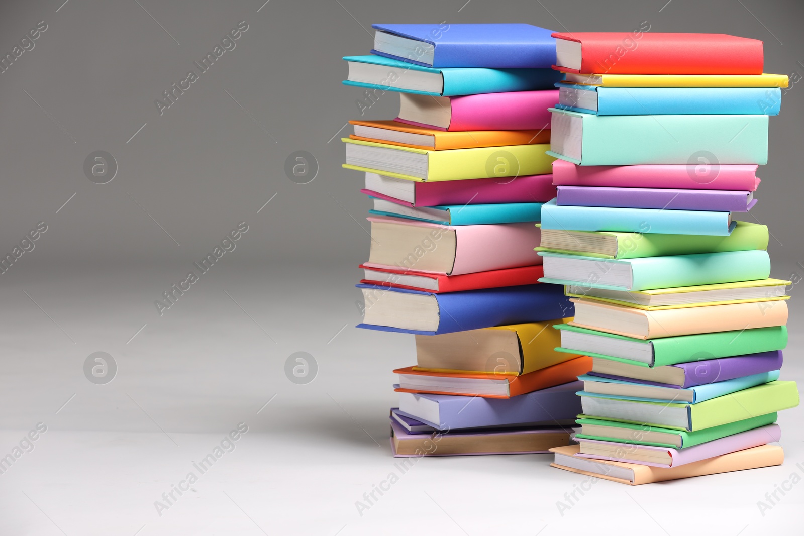 Photo of Stacks of colorful books on light grey background, space for text