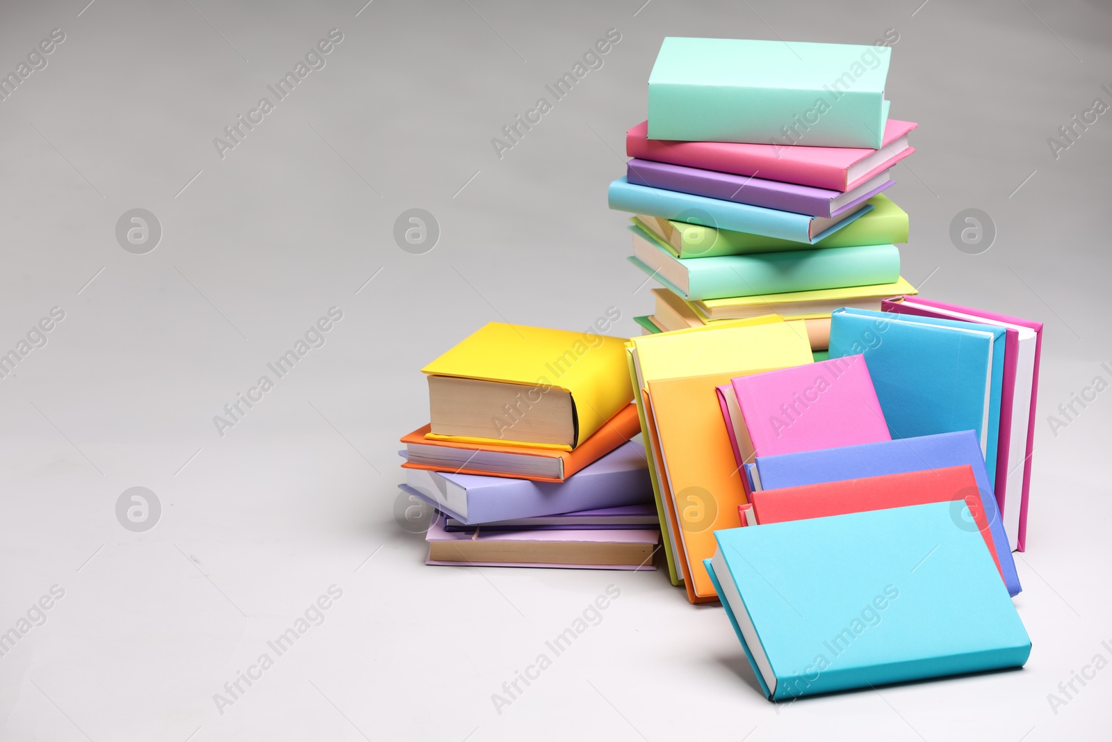 Photo of Stacks of colorful books on light grey background