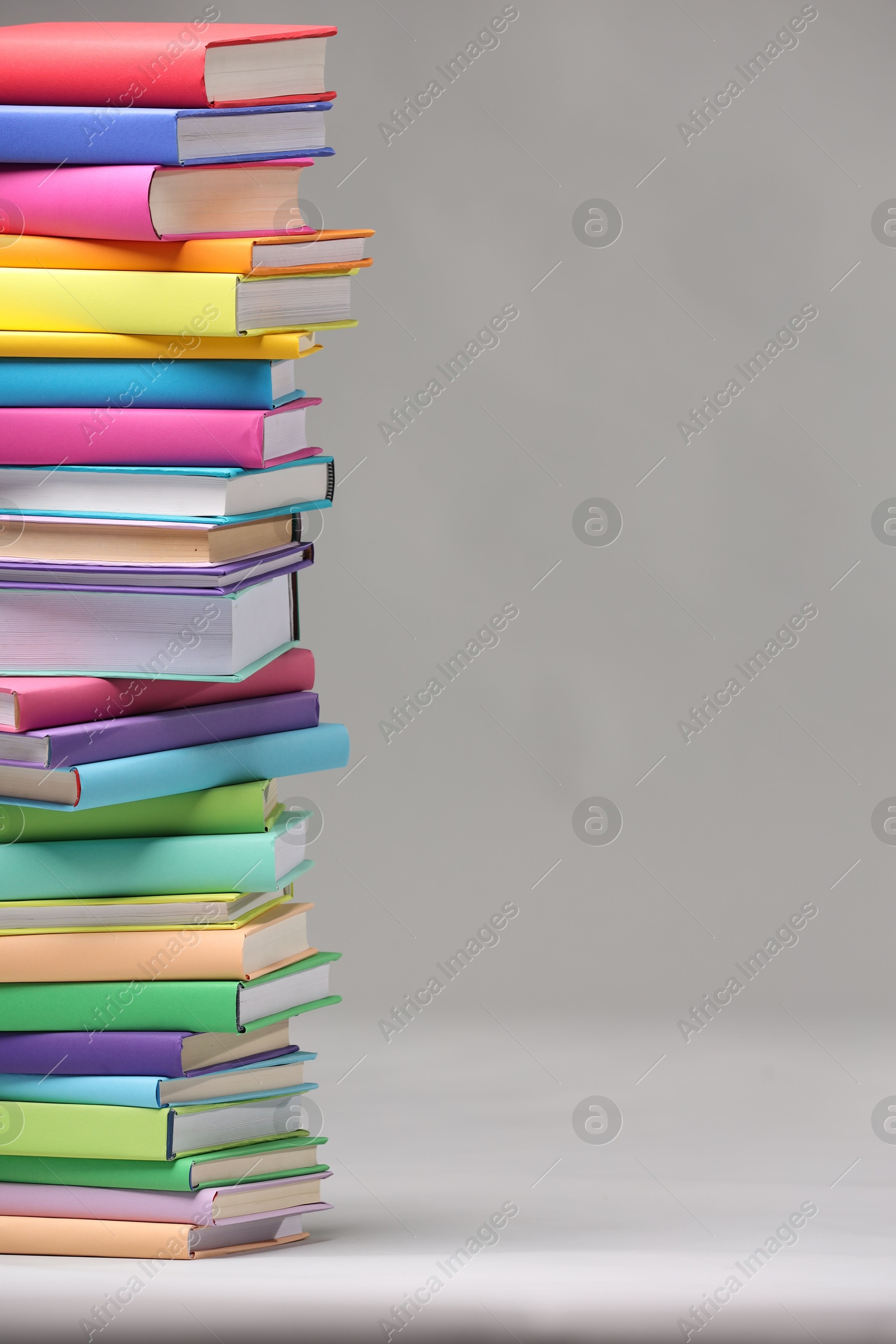 Photo of Stack of colorful books on light grey background, space for text