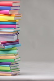 Photo of Stack of colorful books on light grey background, space for text