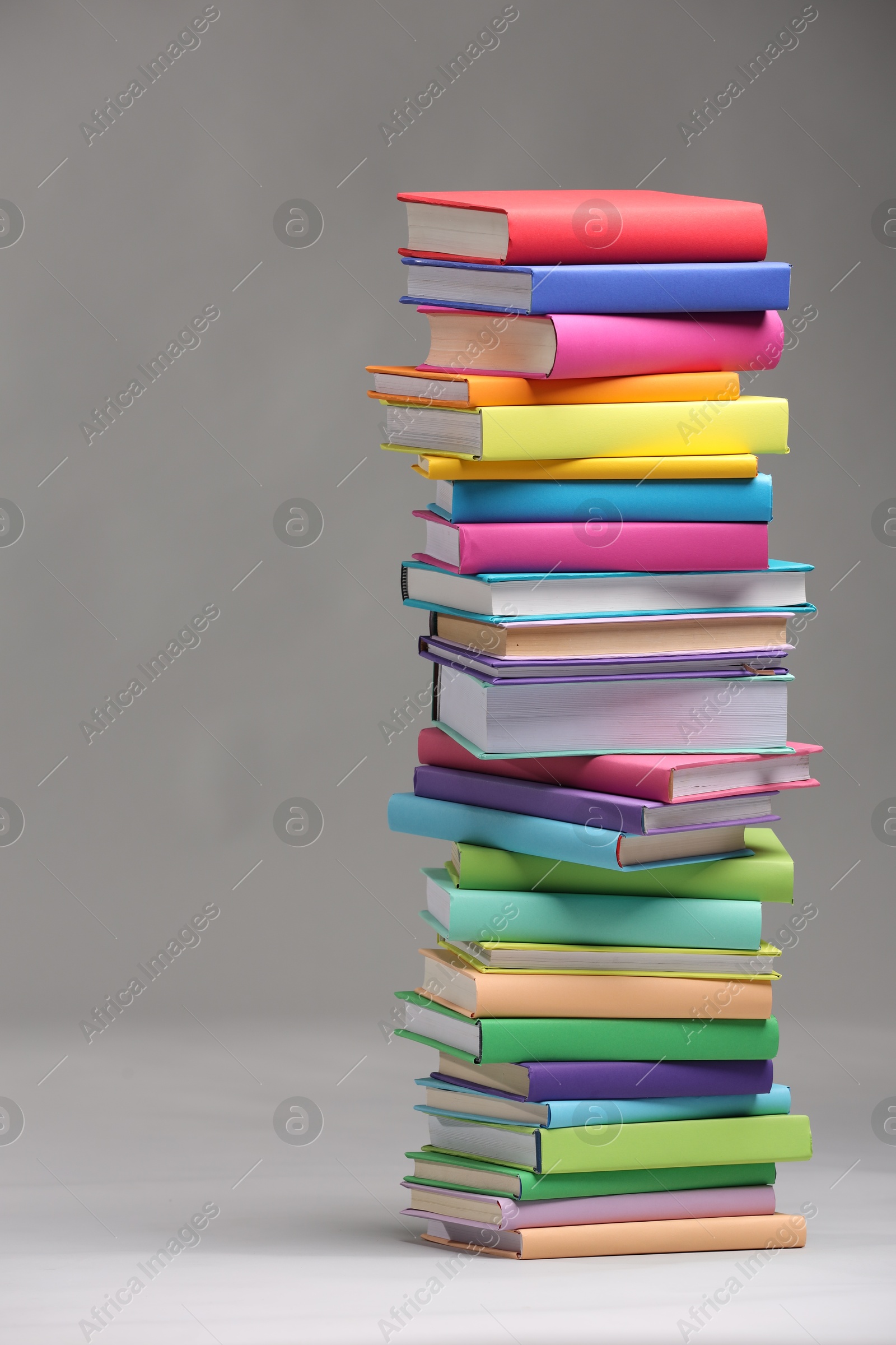 Photo of Stack of colorful books on light grey background