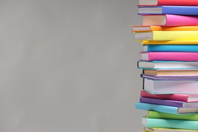 Stack of colorful books on light grey background, space for text