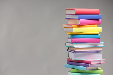 Stack of colorful books on light grey background, space for text