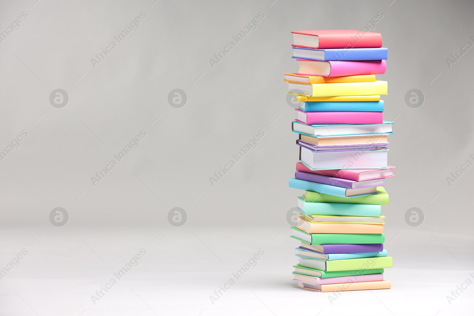 Photo of Stack of colorful books on light grey background, space for text