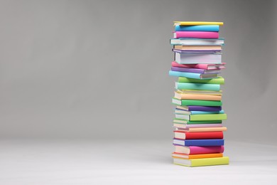 Photo of Stack of colorful books on light grey background, space for text