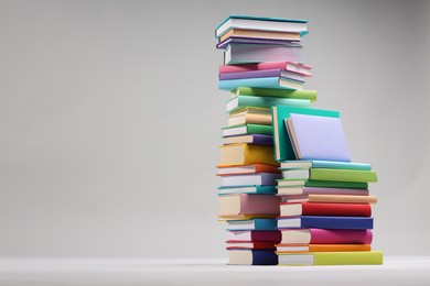 Photo of Stacks of colorful books on light grey background, space for text