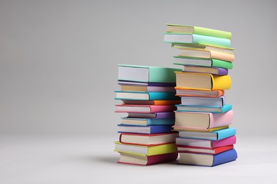 Photo of Stacks of colorful books on light grey background, space for text