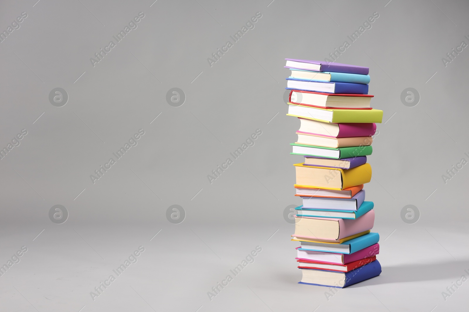 Photo of Stack of colorful books on light grey background, space for text