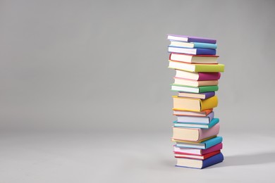 Stack of colorful books on light grey background, space for text