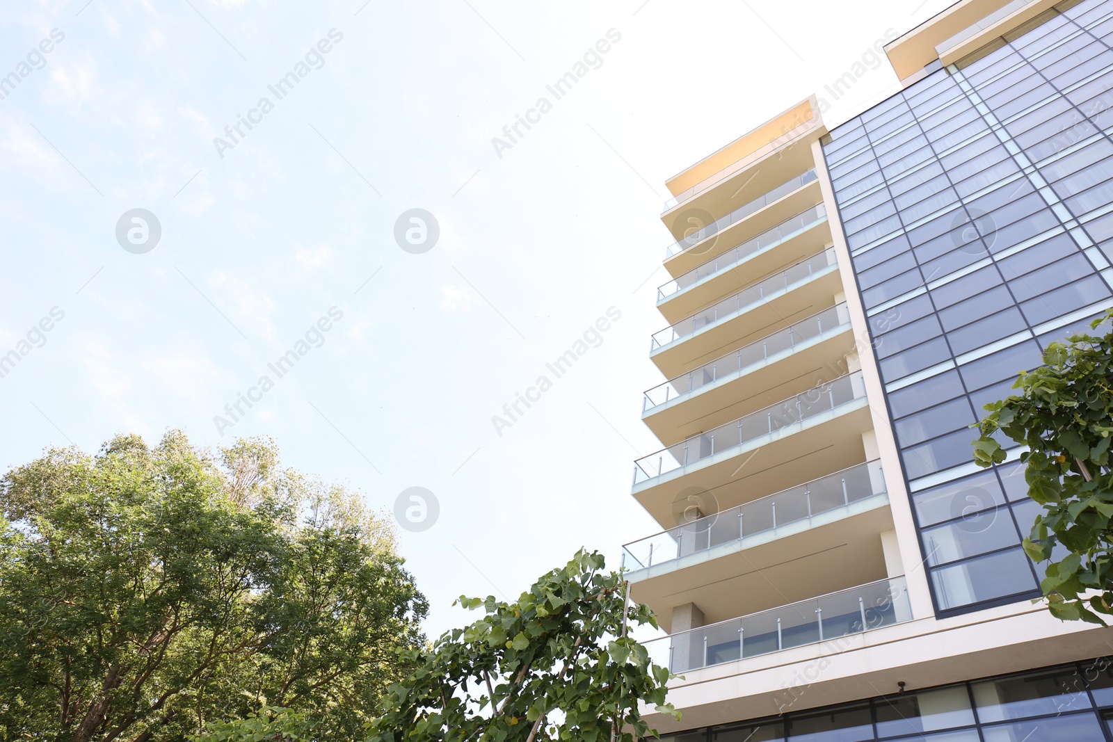Photo of Modern building with big windows outdoors, low angle view. Space for text