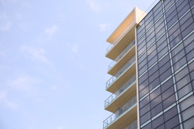 Modern building with big windows against blue sky outdoors, low angle view. Space for text