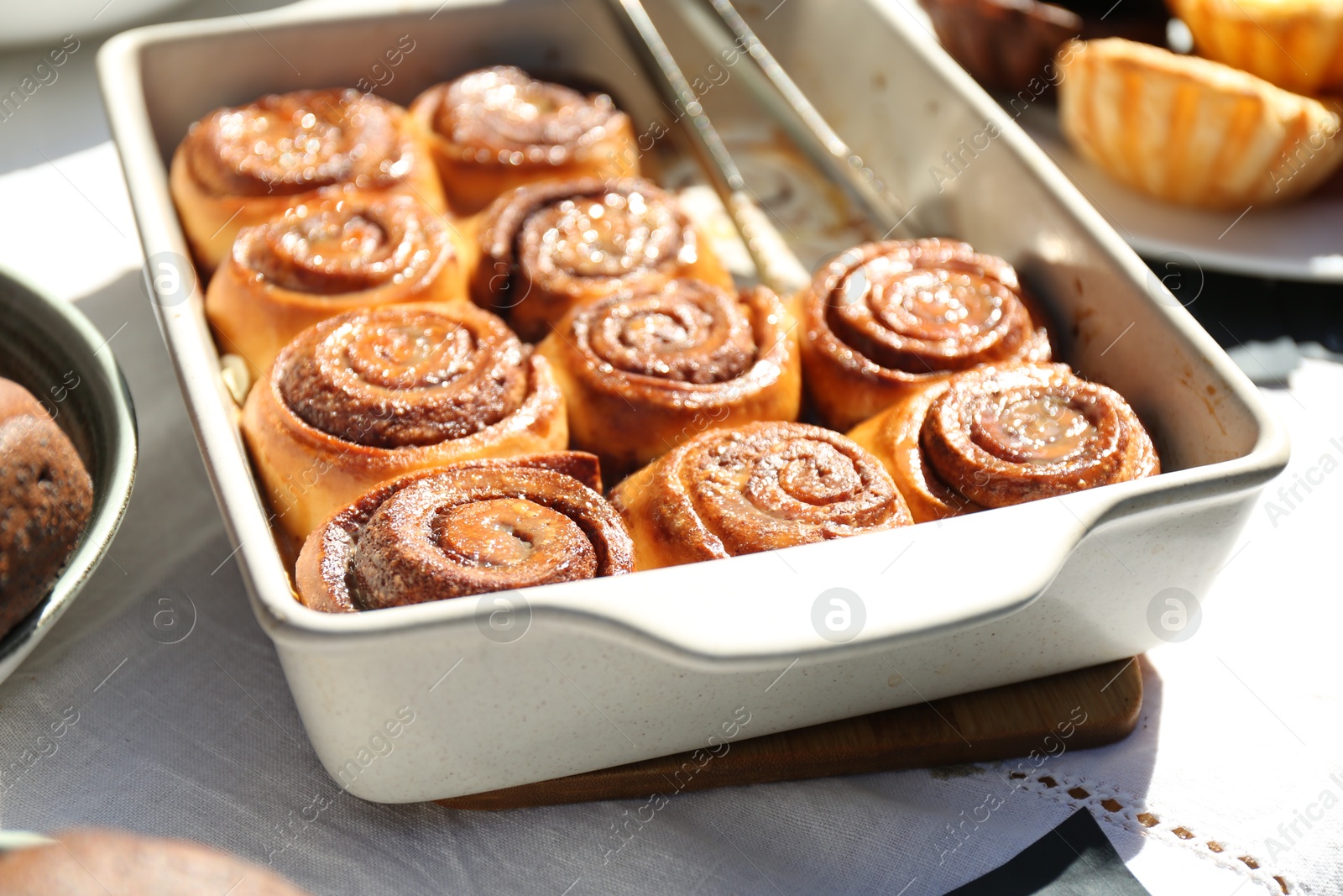 Photo of Tasty cinnamon rolls in baking dish on table outdoors, closeup
