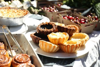 Photo of Tasty tartlets and other pastries on table outdoors, closeup