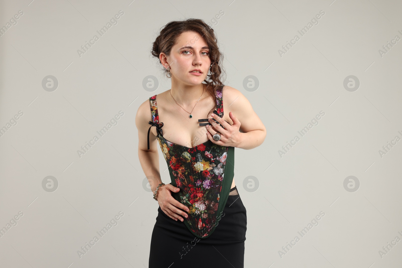 Photo of Beautiful woman in stylish corset posing on light grey background