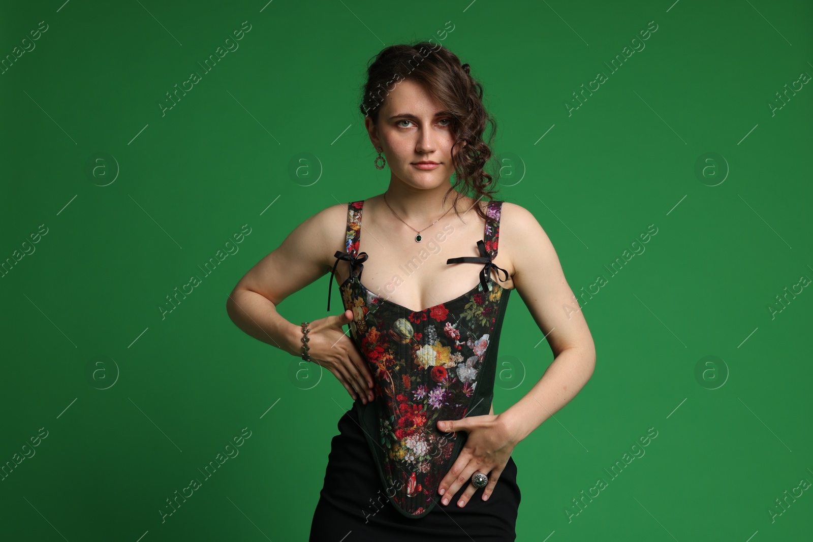 Photo of Beautiful woman in stylish corset posing on green background
