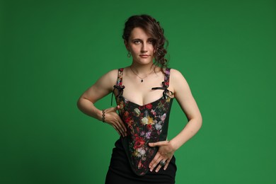 Beautiful woman in stylish corset posing on green background