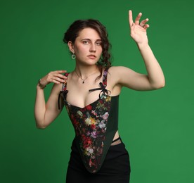 Beautiful woman in stylish corset posing on green background