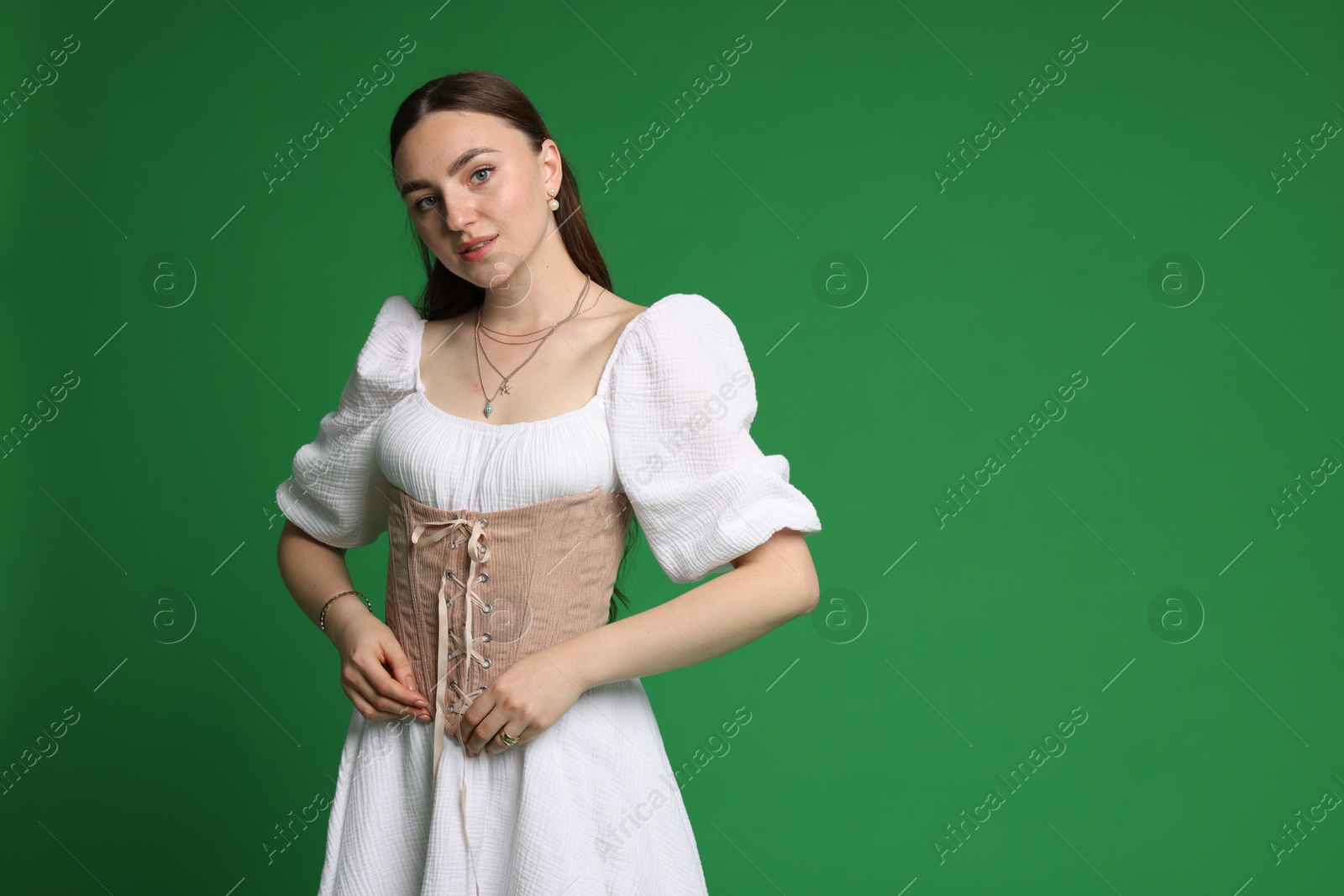 Photo of Beautiful woman in stylish corset on green background. Space for text