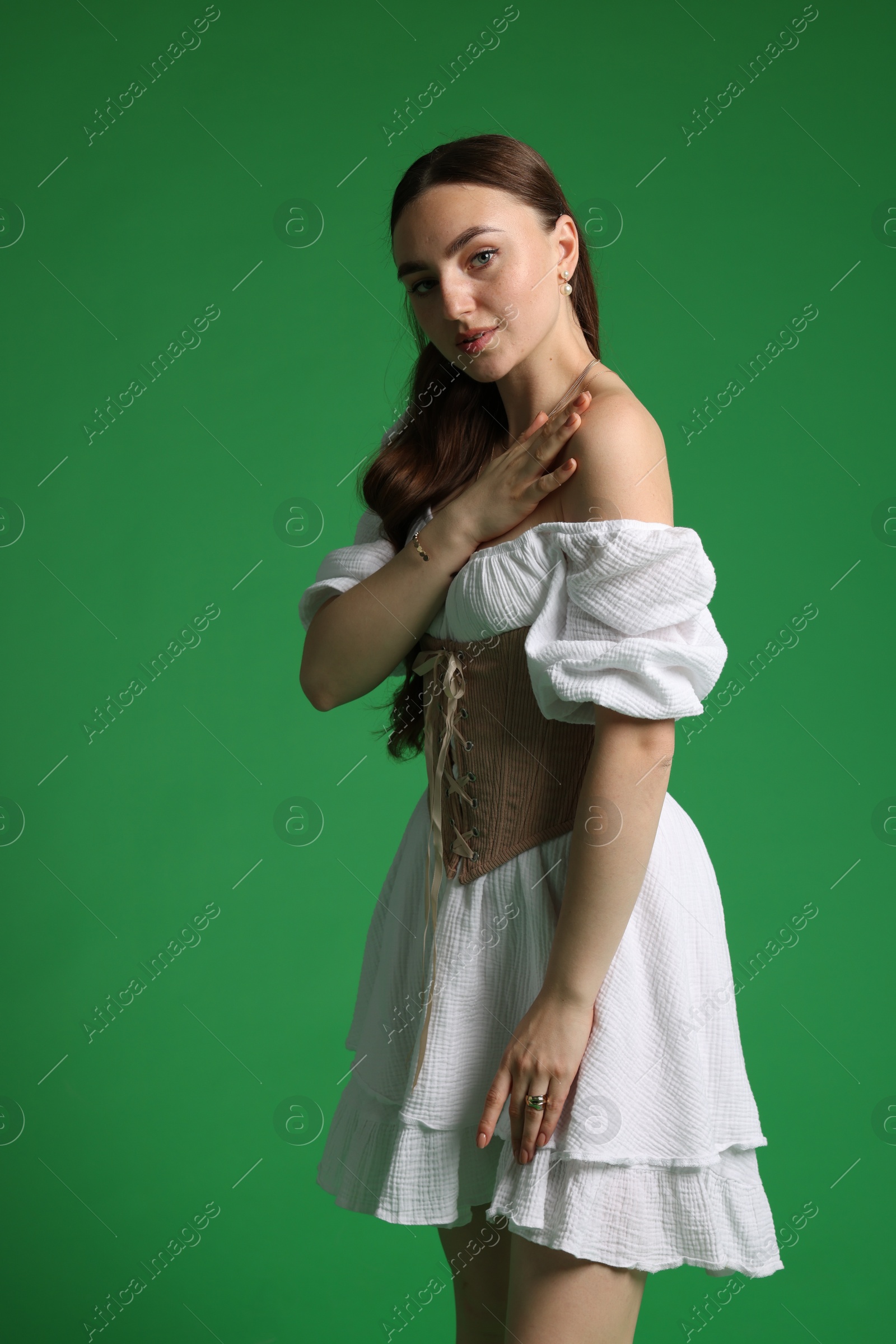 Photo of Beautiful woman in stylish corset posing on green background