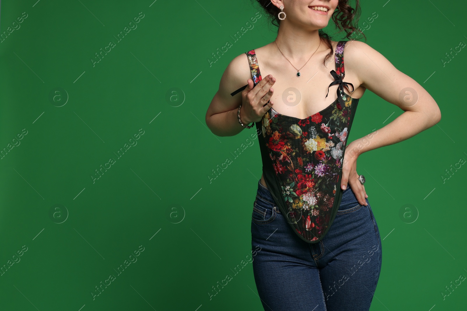 Photo of Smiling woman in stylish corset on green background, closeup. Space for text