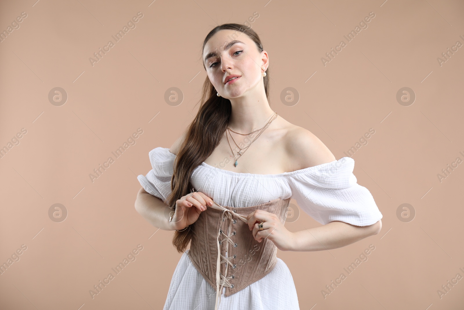 Photo of Beautiful woman in velvet corset on beige background