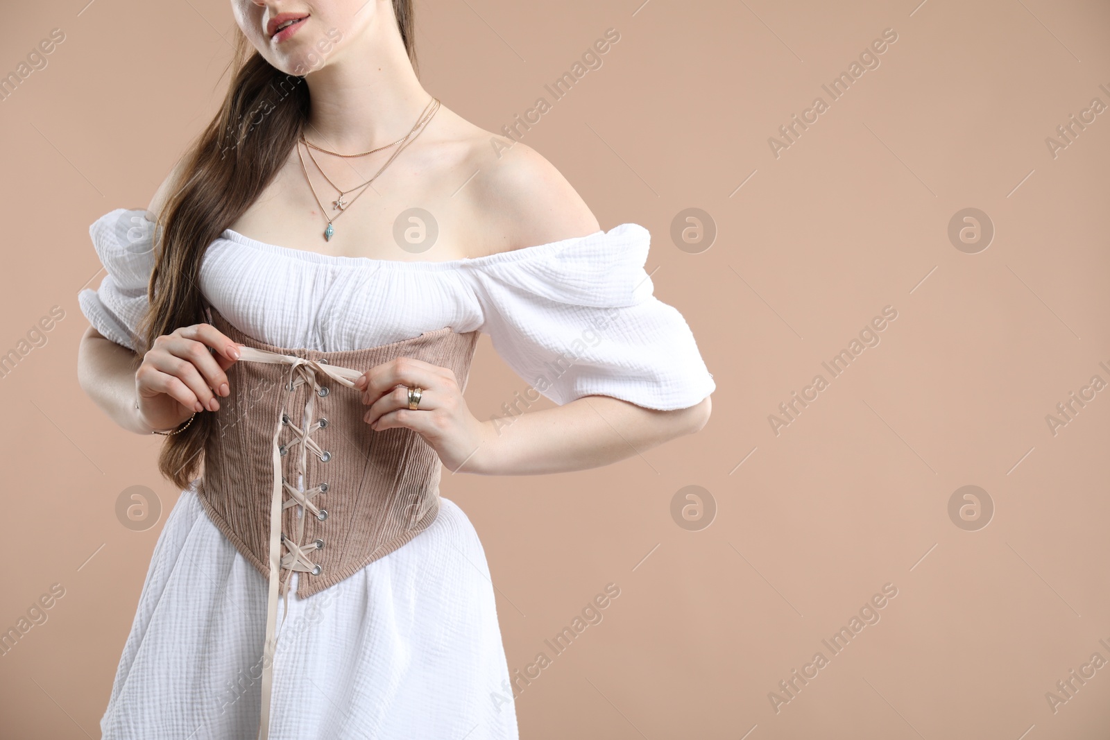 Photo of Woman in velvet corset on beige background, closeup. Space for text