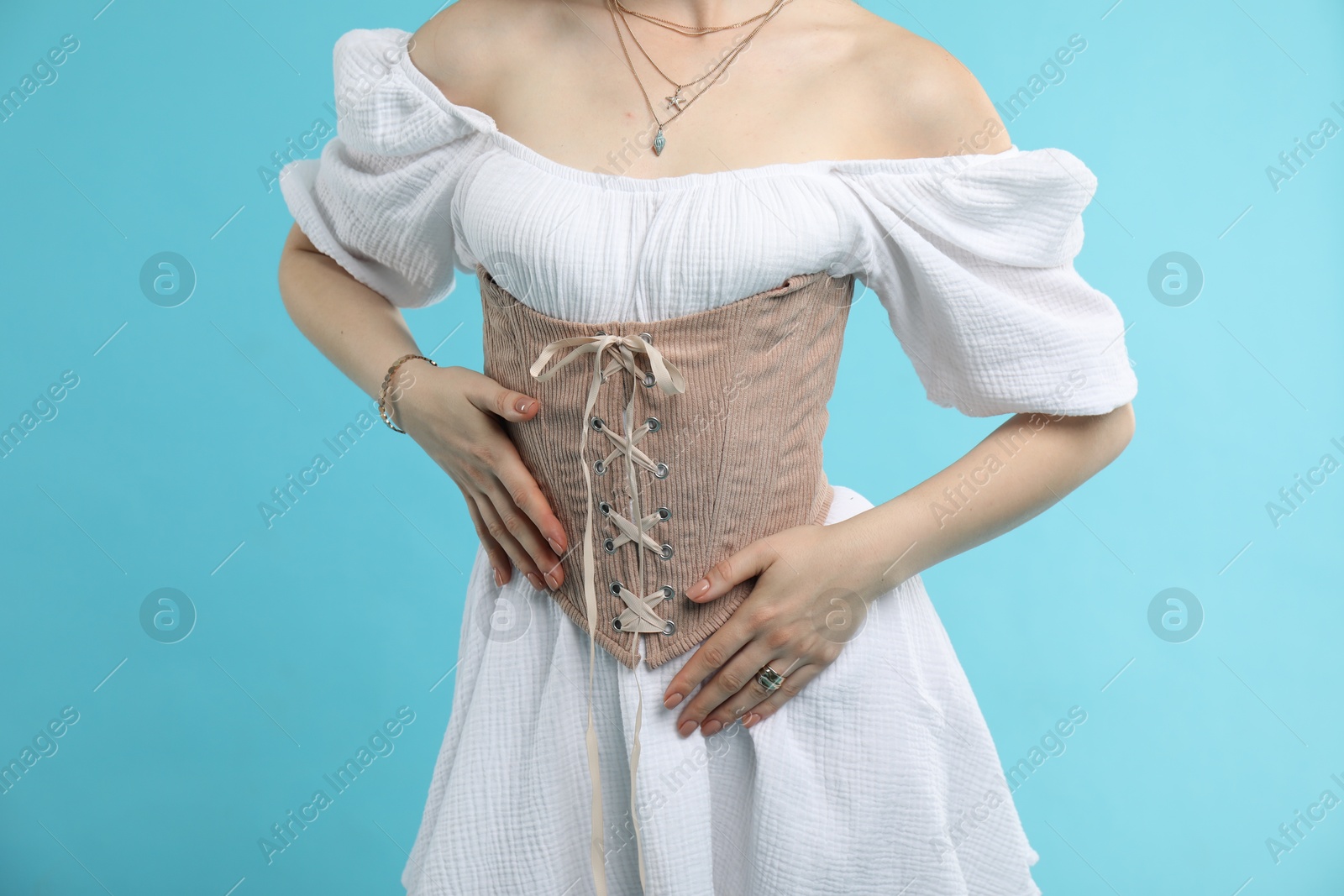 Photo of Woman in velvet corset on light blue background, closeup