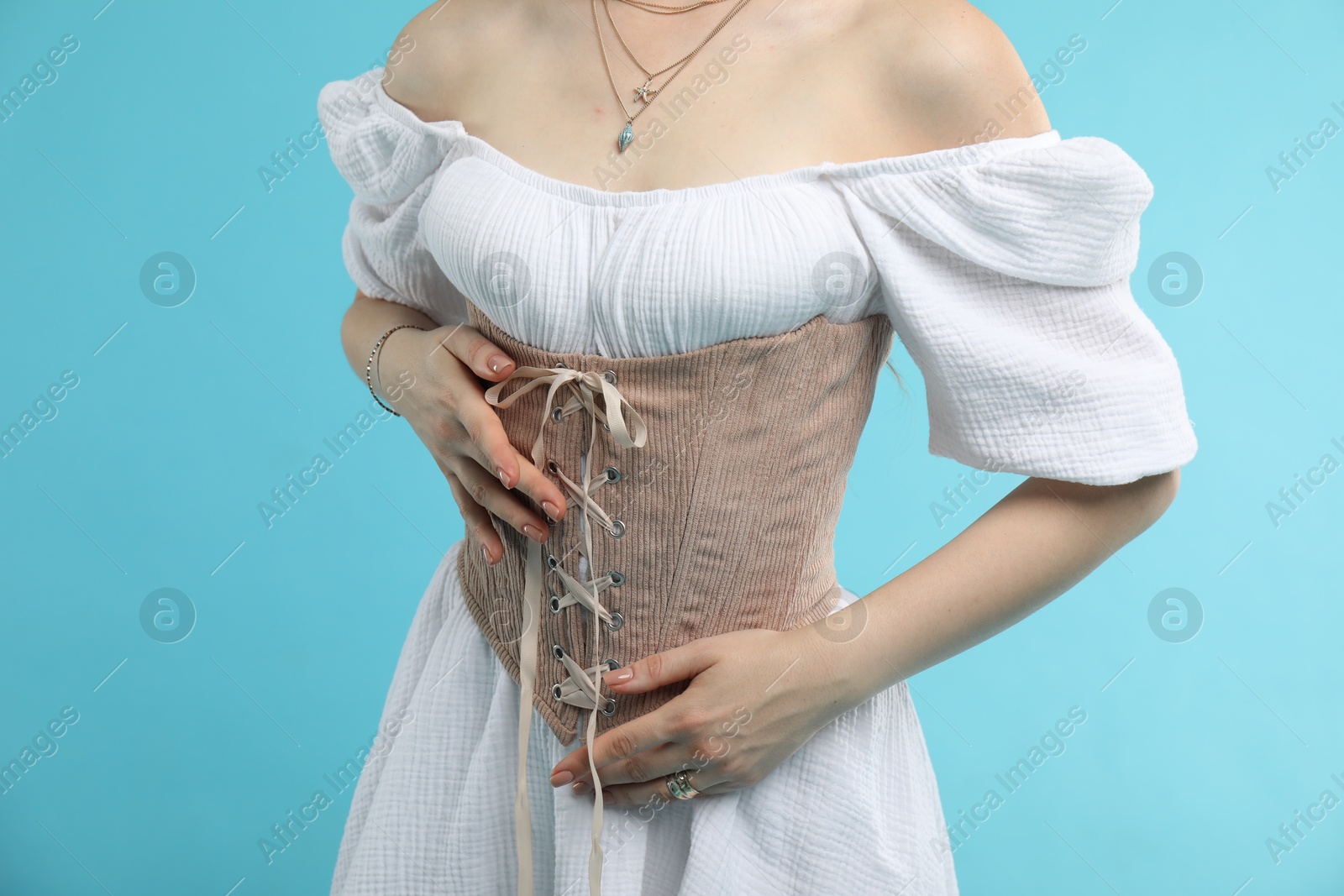 Photo of Woman in velvet corset on light blue background, closeup