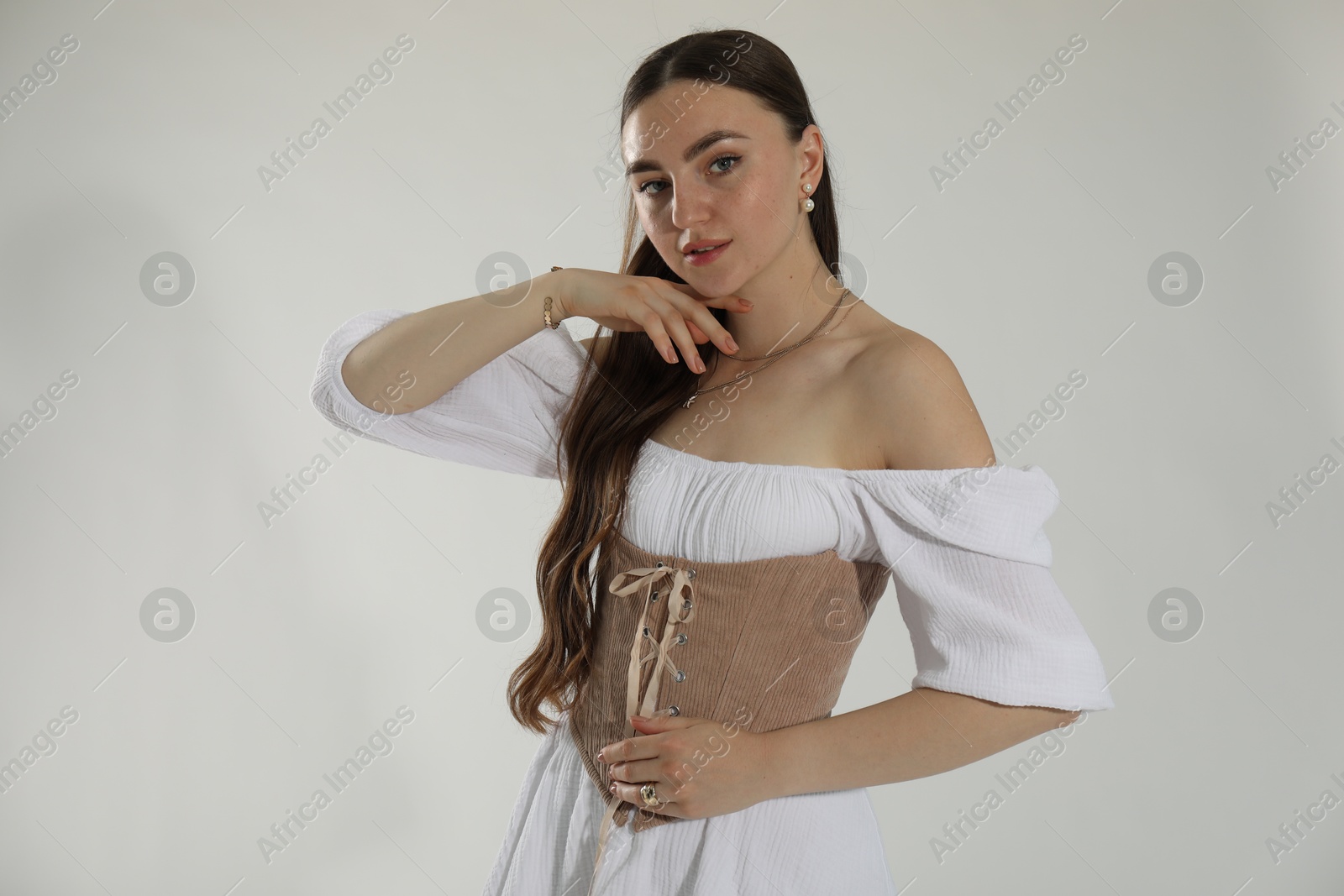 Photo of Beautiful woman in velvet corset posing on white background