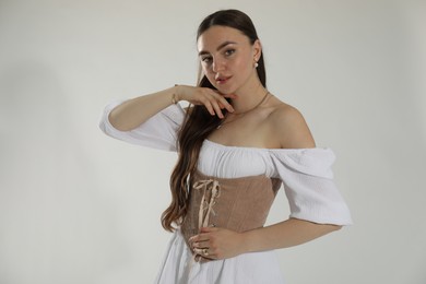 Beautiful woman in velvet corset posing on white background